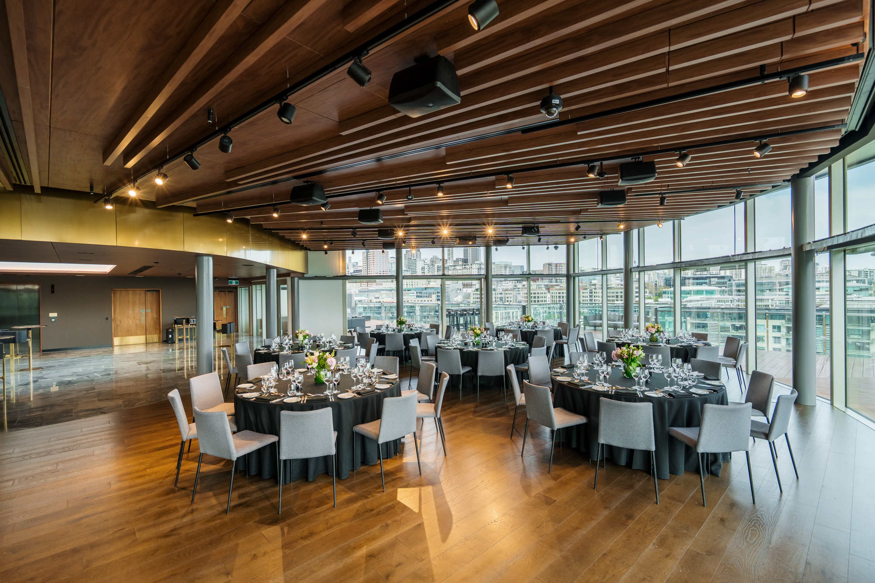 The elegant Harbour Room at Park Hyatt Auckland showing the modern event space with warm timber panels and panoramic Viaduct Harbour views set for a banquet dinner