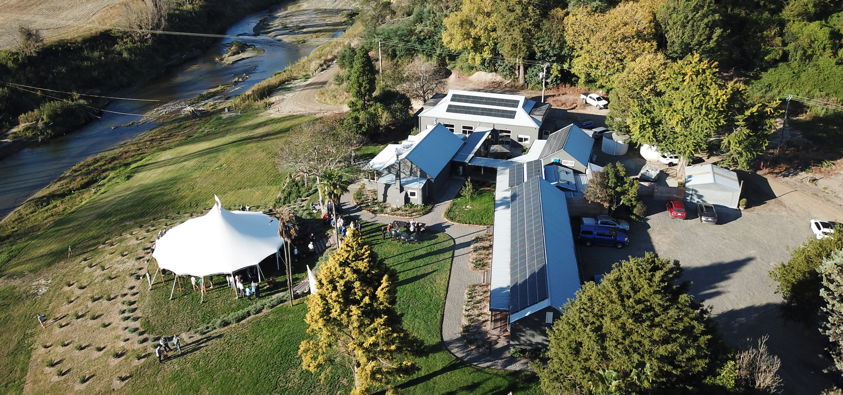 An outdoor event with a white marquee is underway at Omatua, a rural riverside venue in Hawke's Bay.