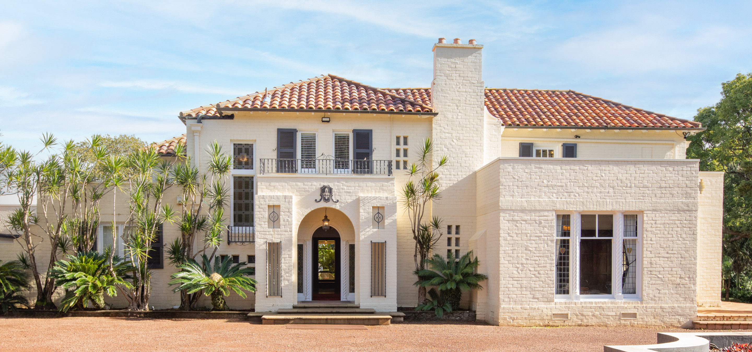 The Spanish-style entrance of Puketutu Island Estate in Auckland, featuring an arched doorway and terracotta roof.