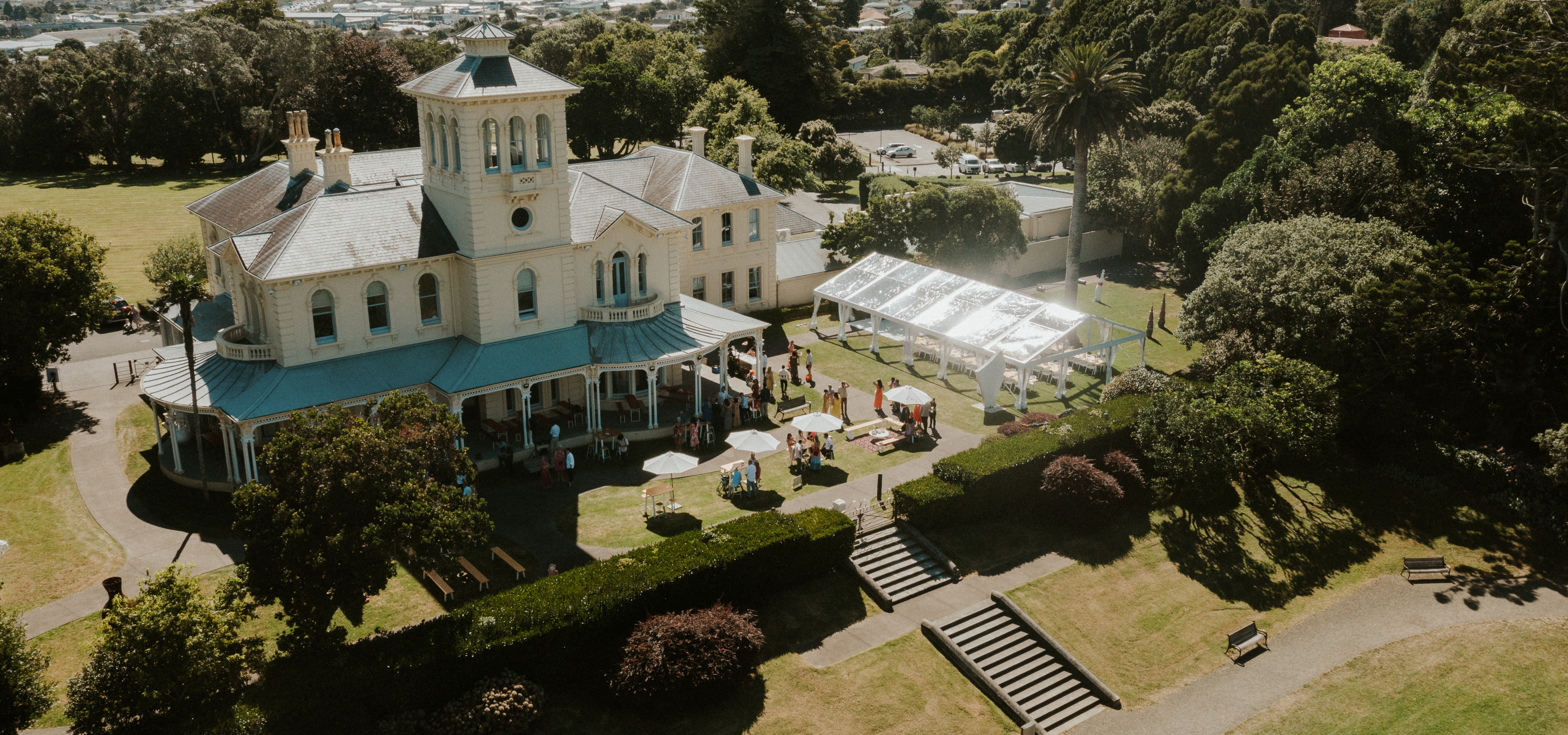 An outdoor gathering is underway on the lawns of the Italianate Pah Homestead, home to The Arts House Trust in Auckland.