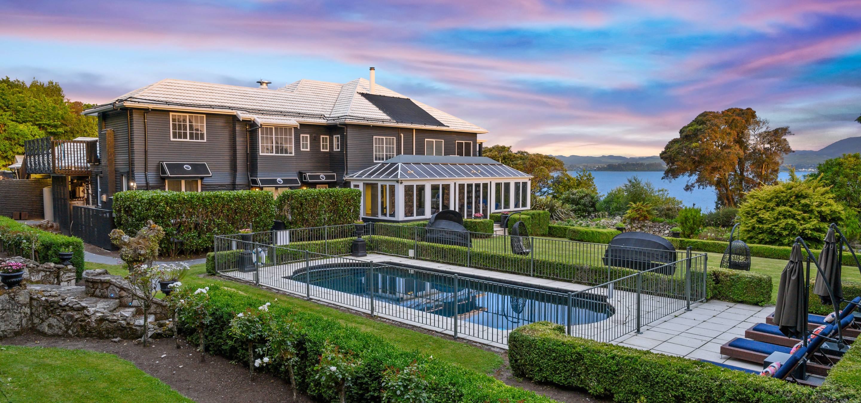 An outdoor pool and Victorian-styled gardens at the elegant Black Swan Lakeside Boutique Hotel in Rotorua, overlooking the lake.