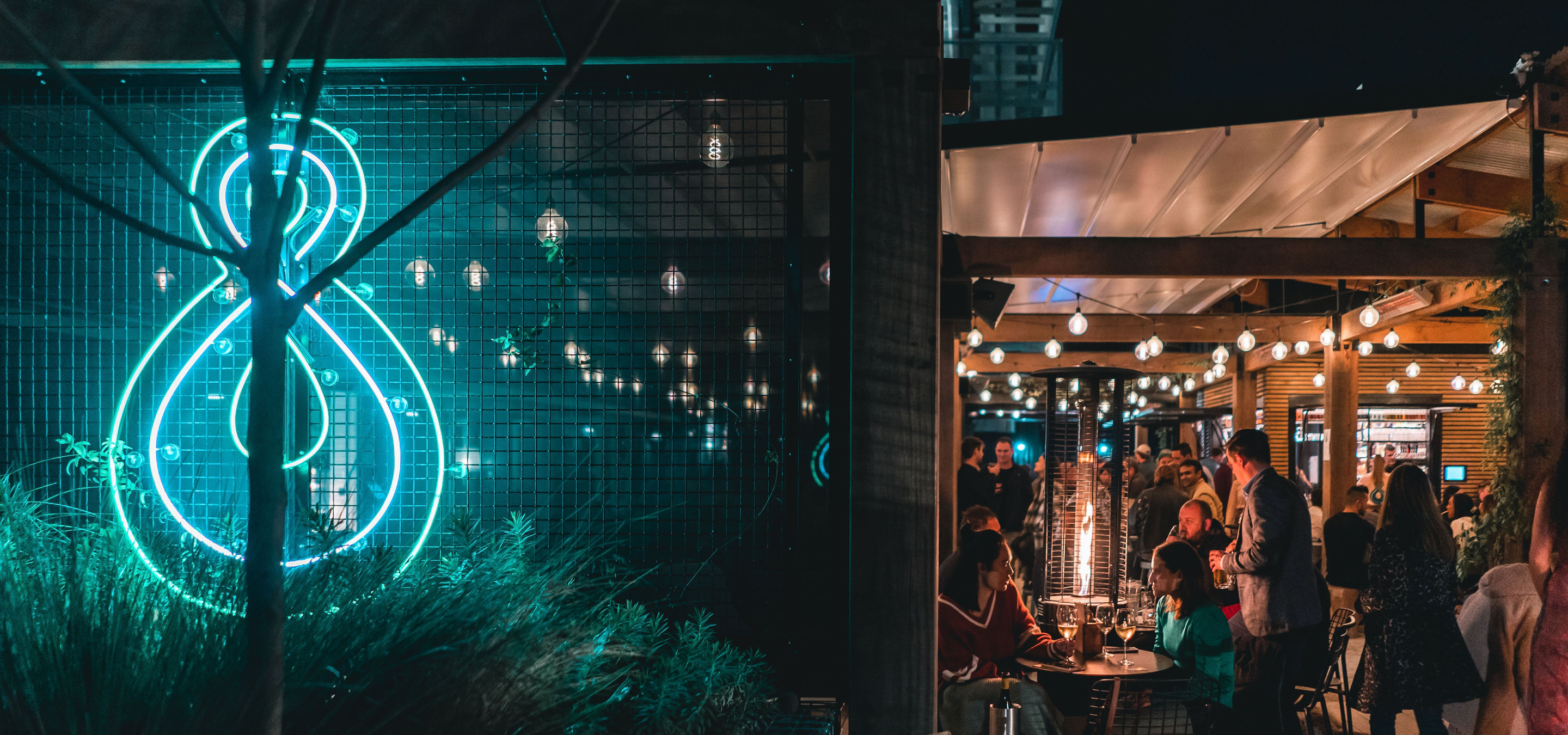 Fantail & Turtle, Auckland's trendy, architecturally designed outdoor bar, shines with ambient lights and a neon sign for evening gatherings.