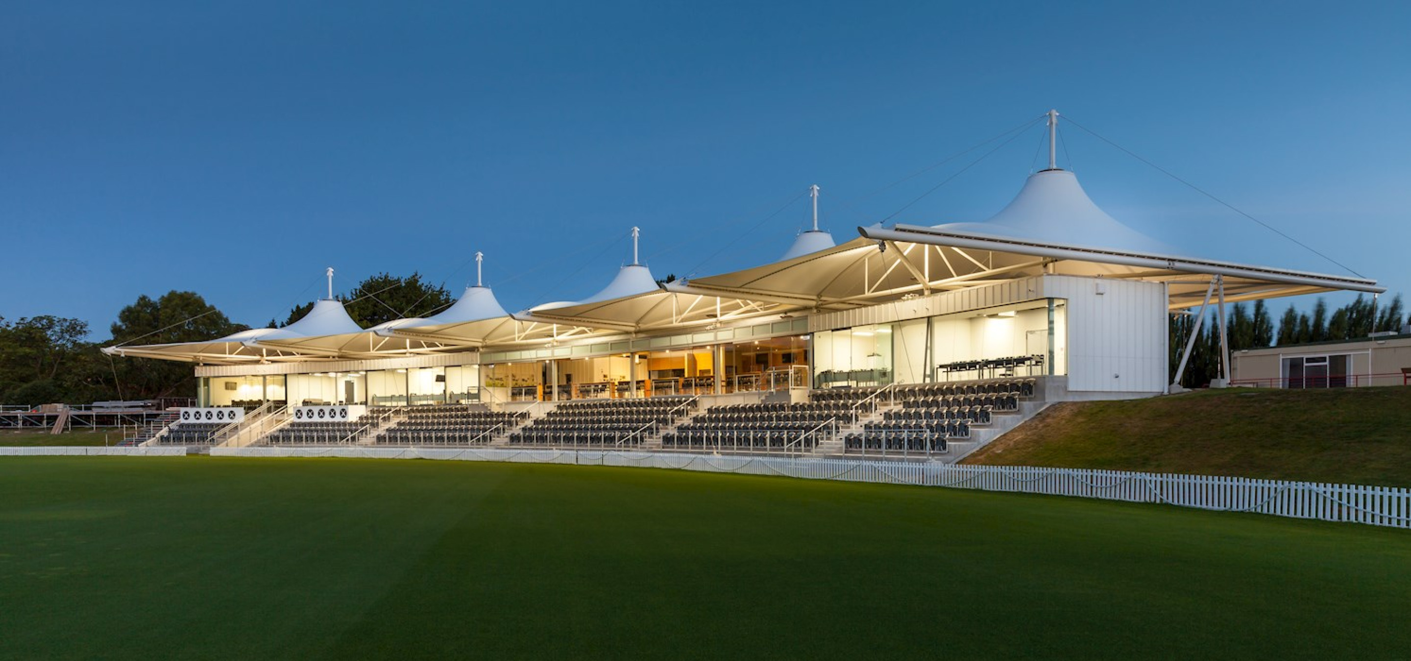 The Hadlee Pavilion's distinctive tensile roof structure illuminates the spectator stands and cricket field at Hagley Oval, Christchurch.