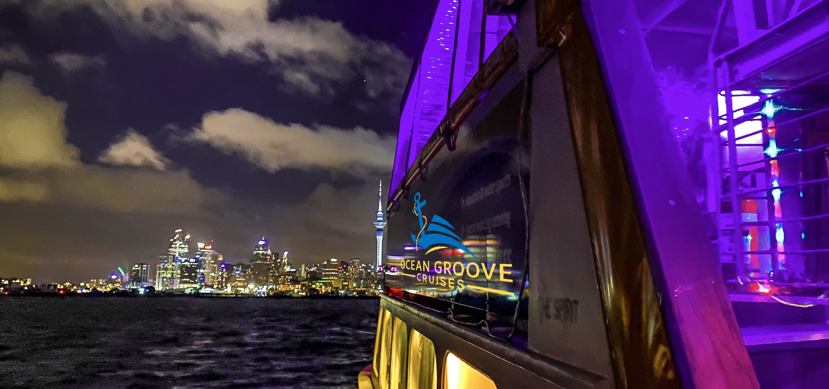 Ocean Groove Cruises' purple-lit party boat cruises Auckland Harbour against the sparkling city skyline.