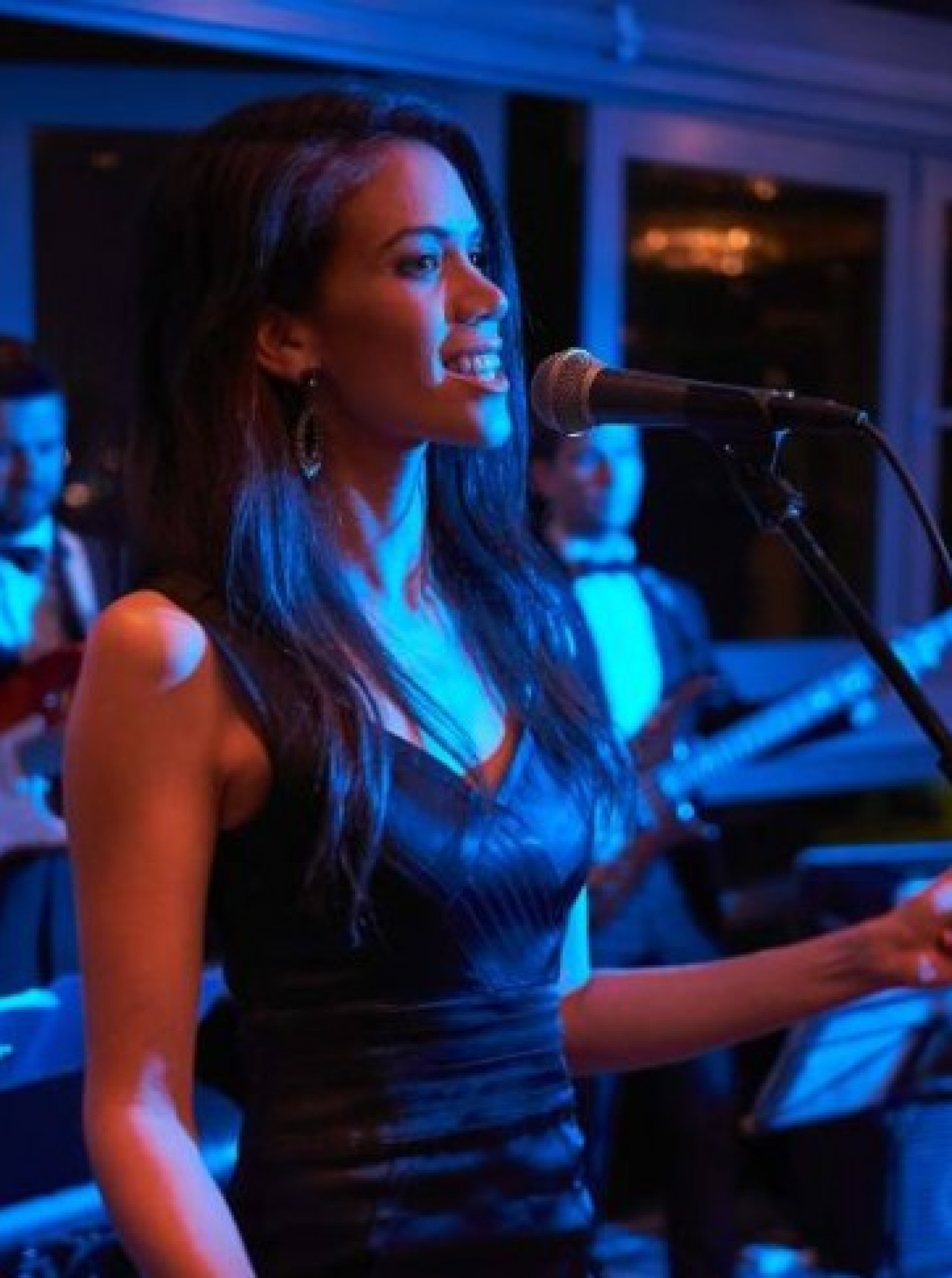 A vibrant live performance by Auckland's Quantum Blue, featuring a vocalist under atmospheric blue lighting.