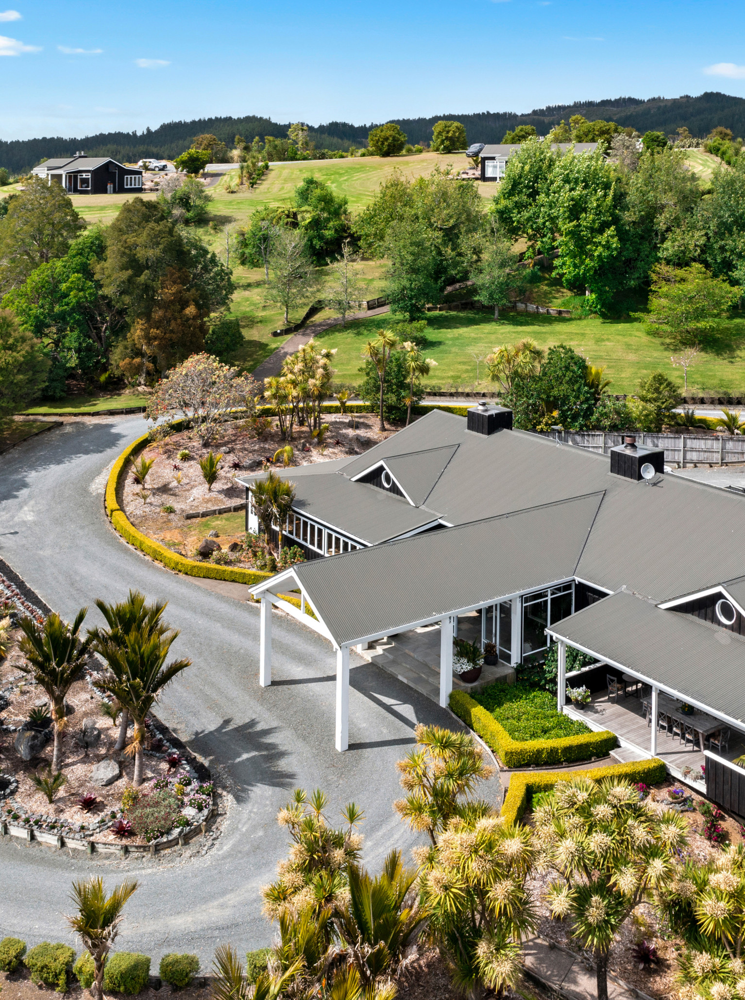 Aerial view of Woodhouse Mountain Lodge, Auckland, showcasing its contemporary lodge architecture amidst rolling green hills.