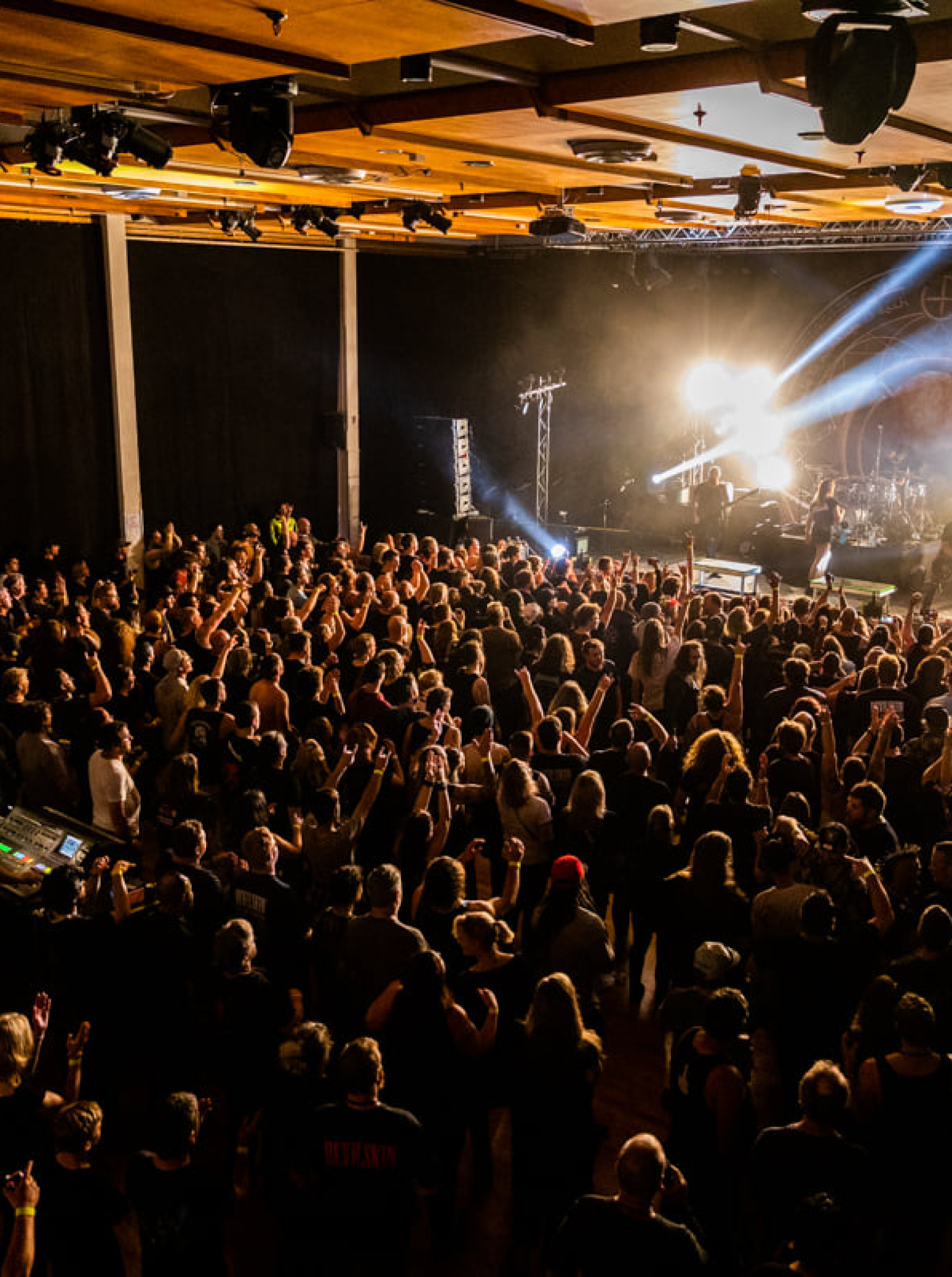 A vibrant concert crowd fills Forum North's Whangarei performance space, featuring a distinctive timber-lined ceiling.