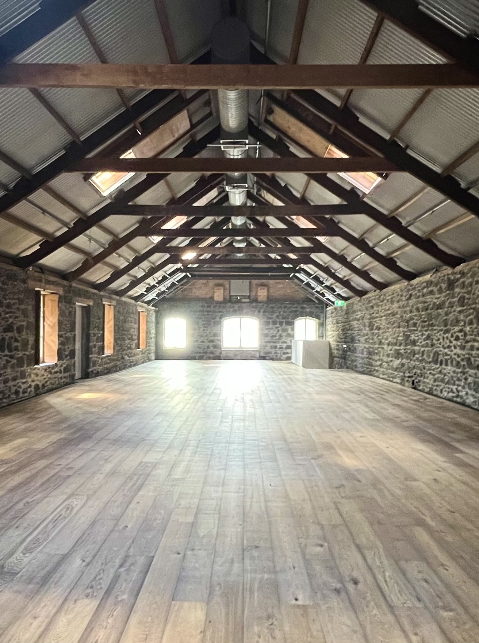 BRAD'S Warehouse, Auckland, offers an industrial-chic event space with bluestone walls, wooden floors, and exposed beams.