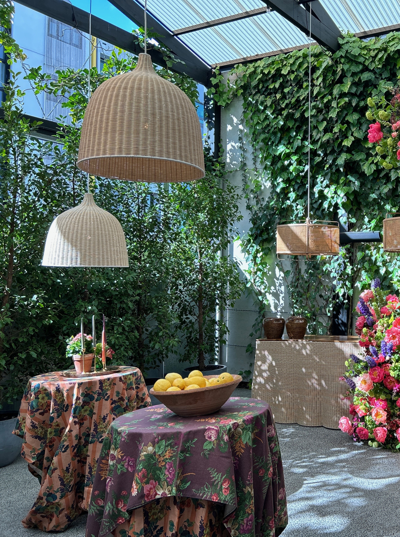 A chic, green-covered courtyard event space at Space On Crummer, Auckland, with lush floral arrangements and wicker lighting.