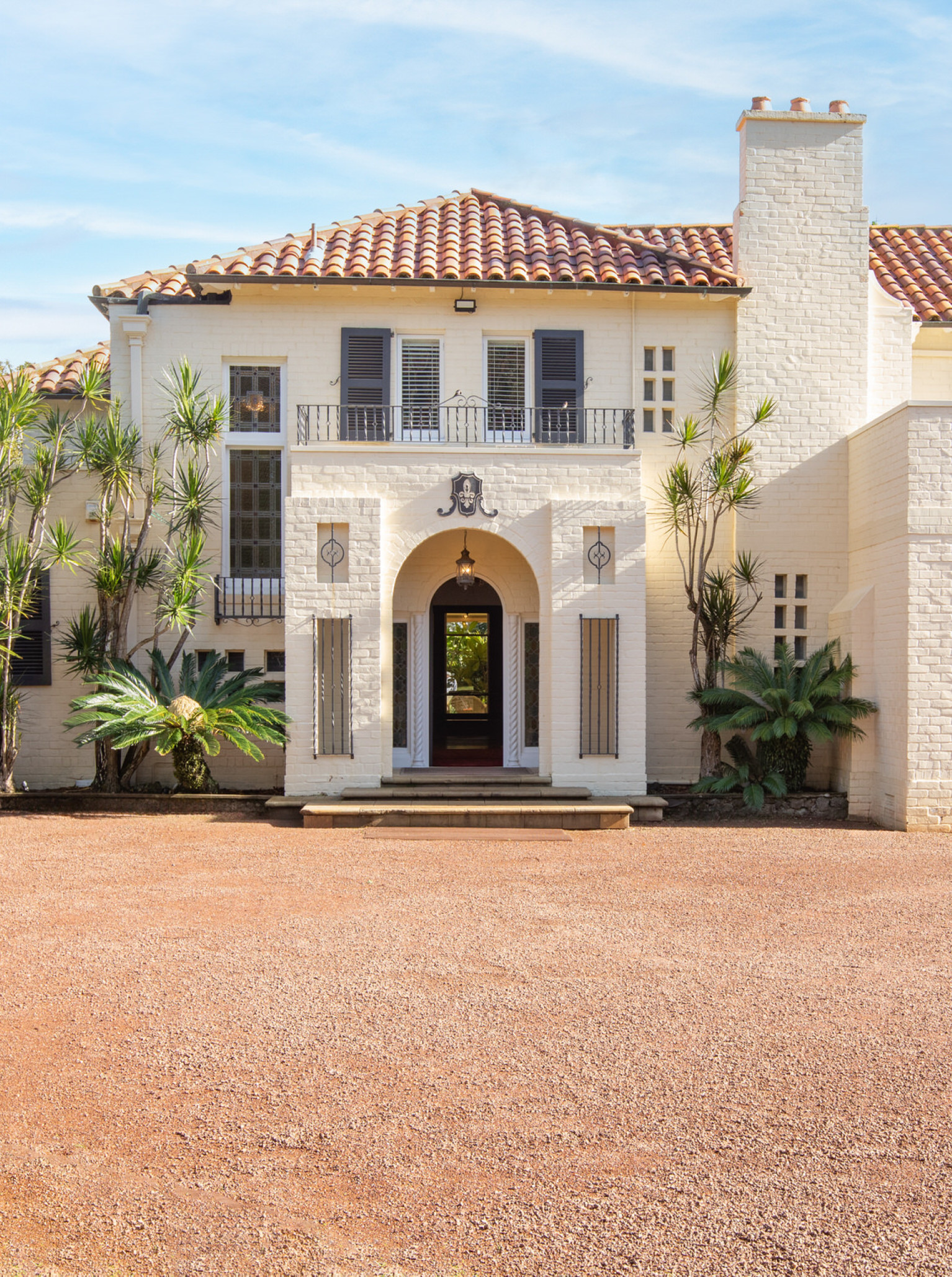The Spanish-style entrance of Puketutu Island Estate in Auckland, featuring an arched doorway and terracotta roof.