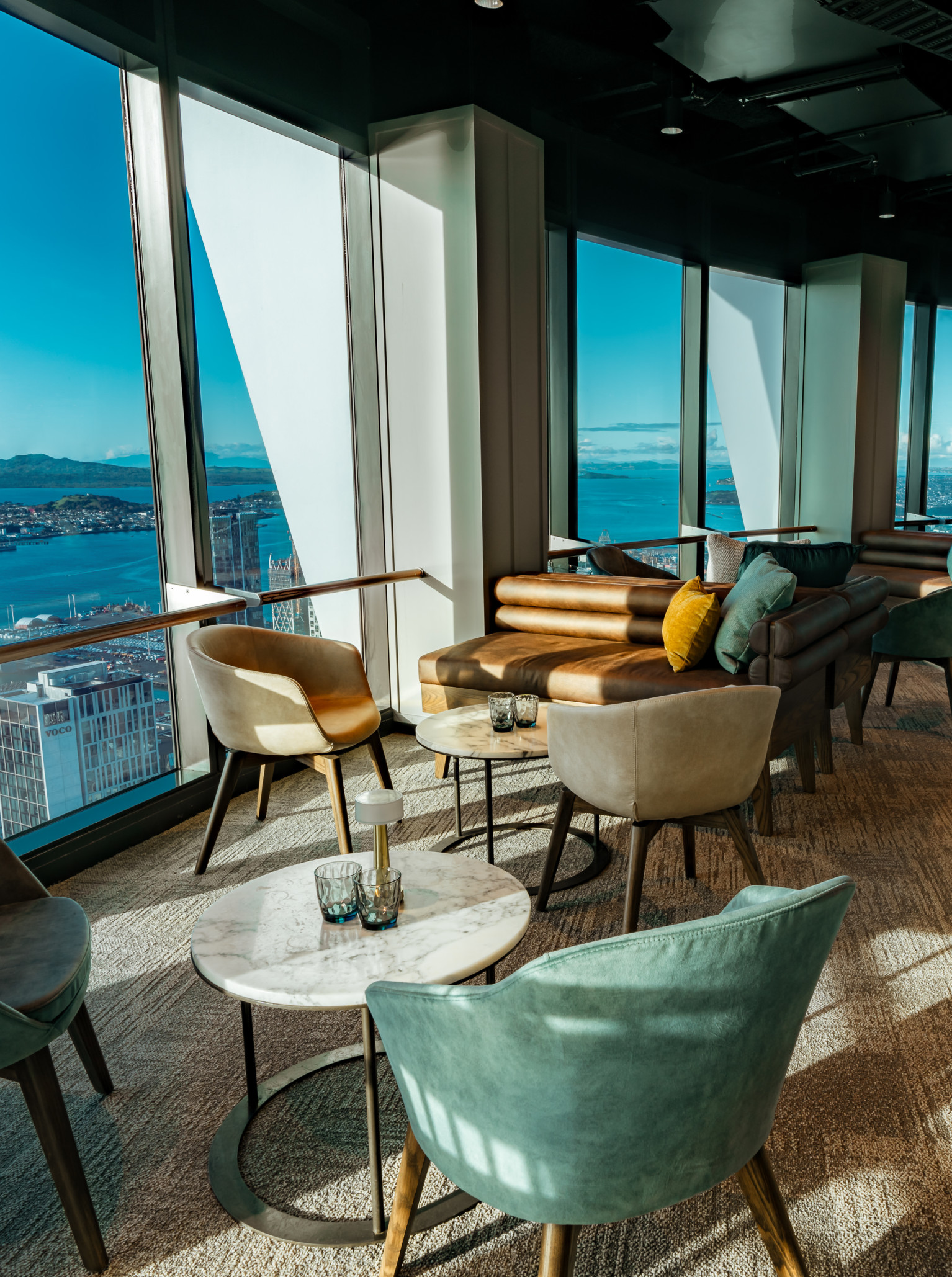 An opulent high-rise lounge at SkyBar in Auckland offers panoramic views of the city and harbour through its floor-to-ceiling windows.