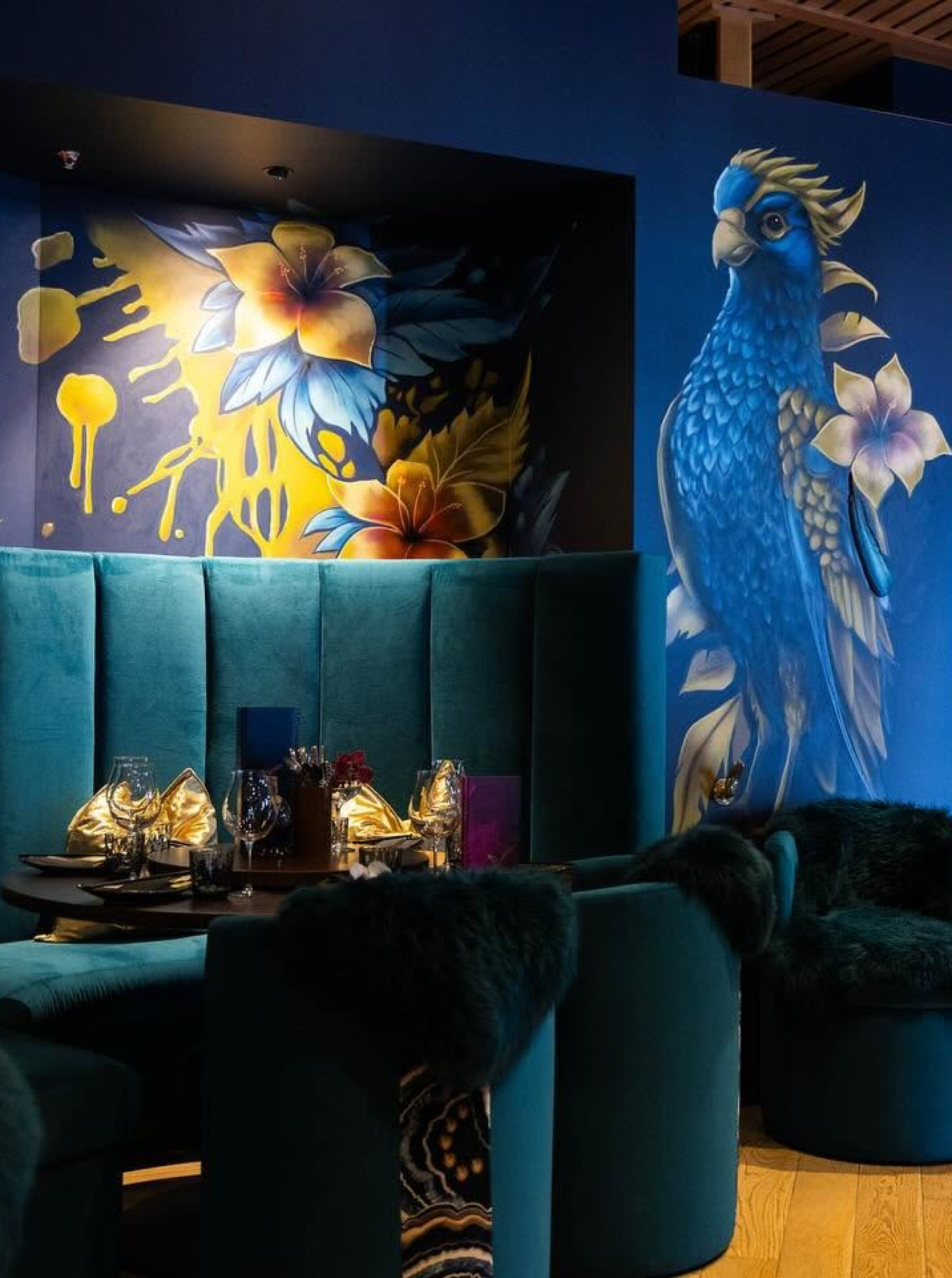 A vibrant dining area at Manu in Christchurch features luxurious teal seating and bold murals reflecting its Pacifica-glam style.