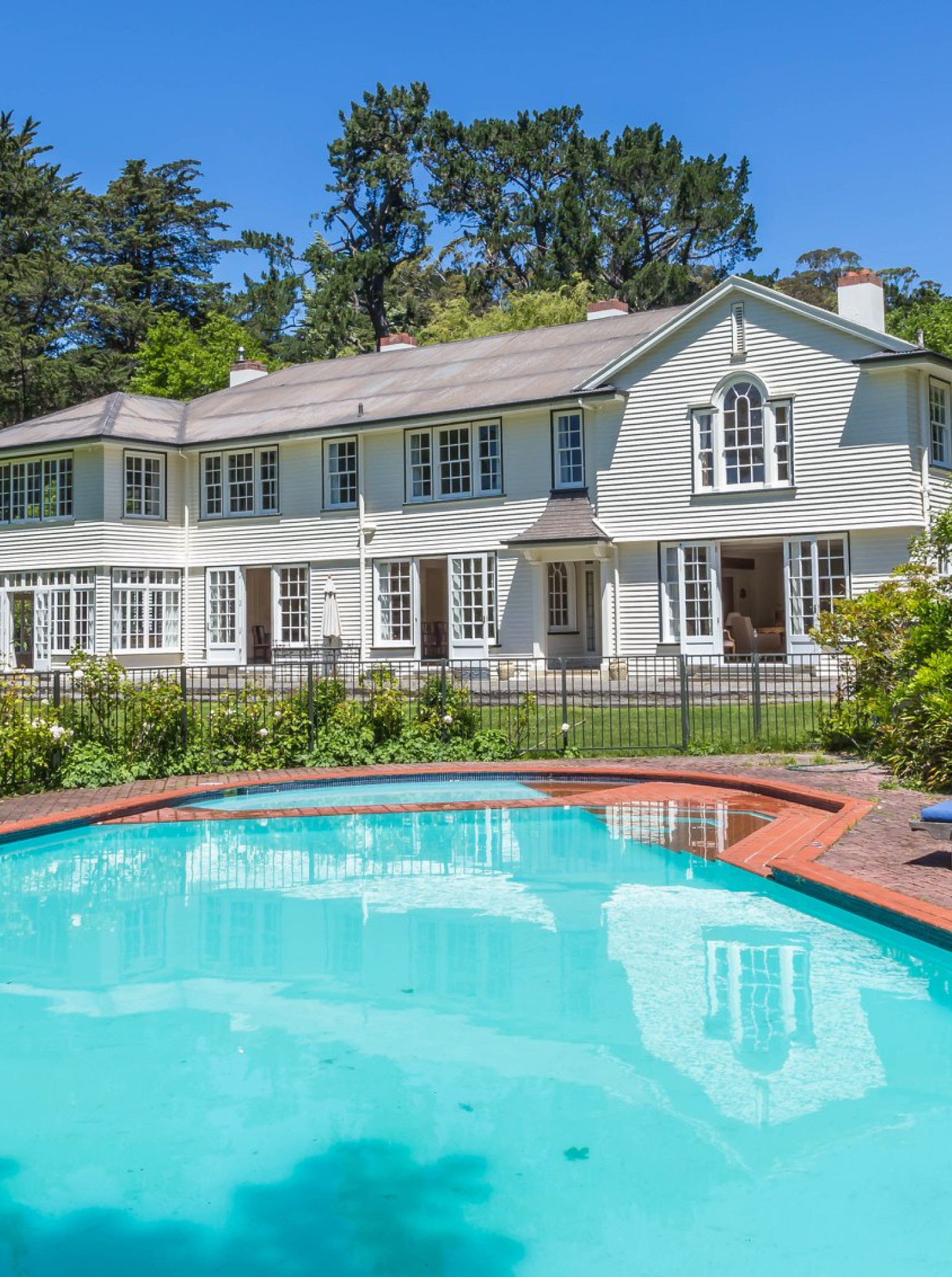 An inviting swimming pool and loungers beside the elegant, Hamptons-inspired historic homestead at Tipapa Estate, Canterbury.