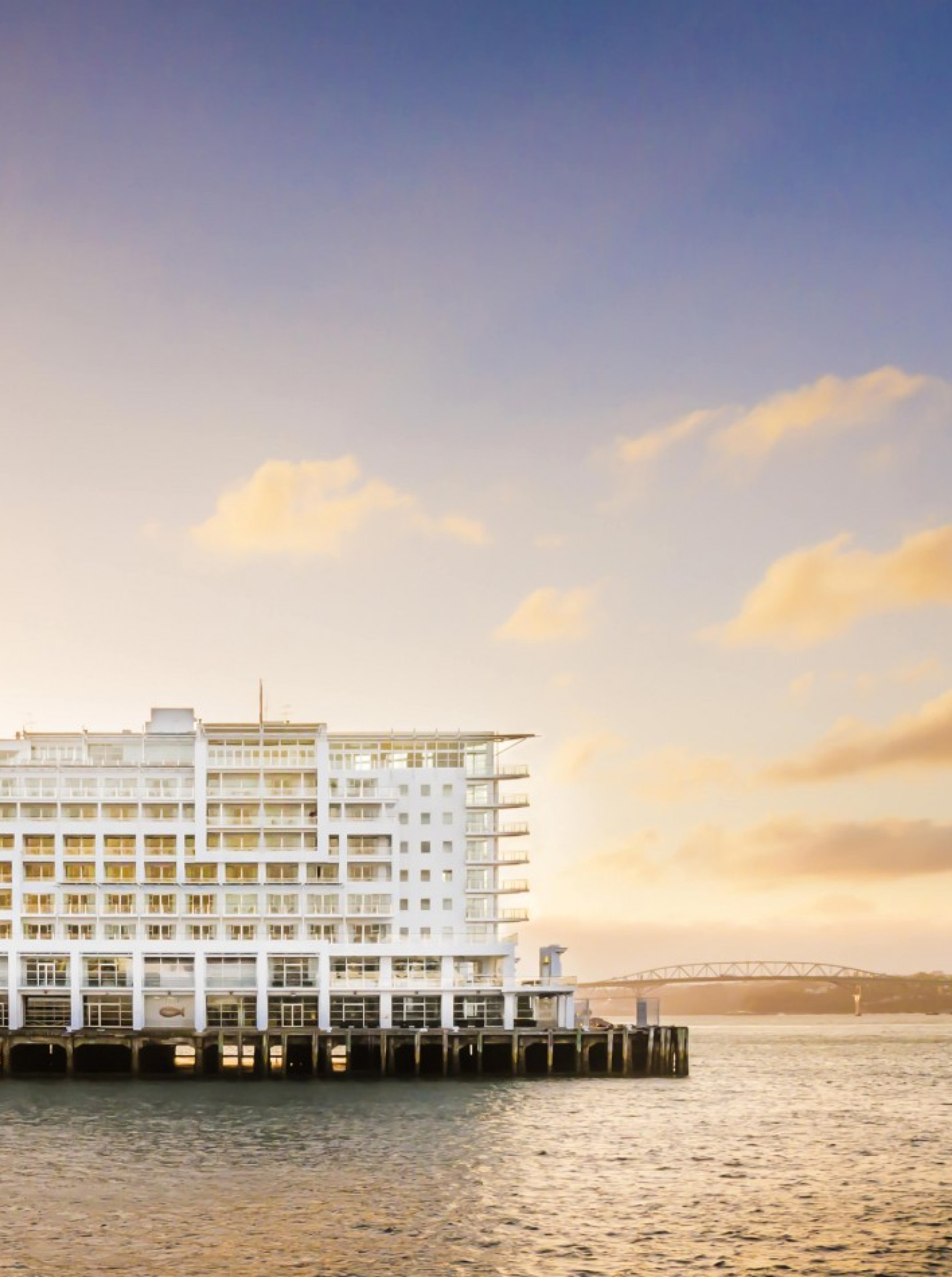 An exterior view of the contemporary, nautical-inspired Hilton Auckland hotel on Princes Wharf at sunset.