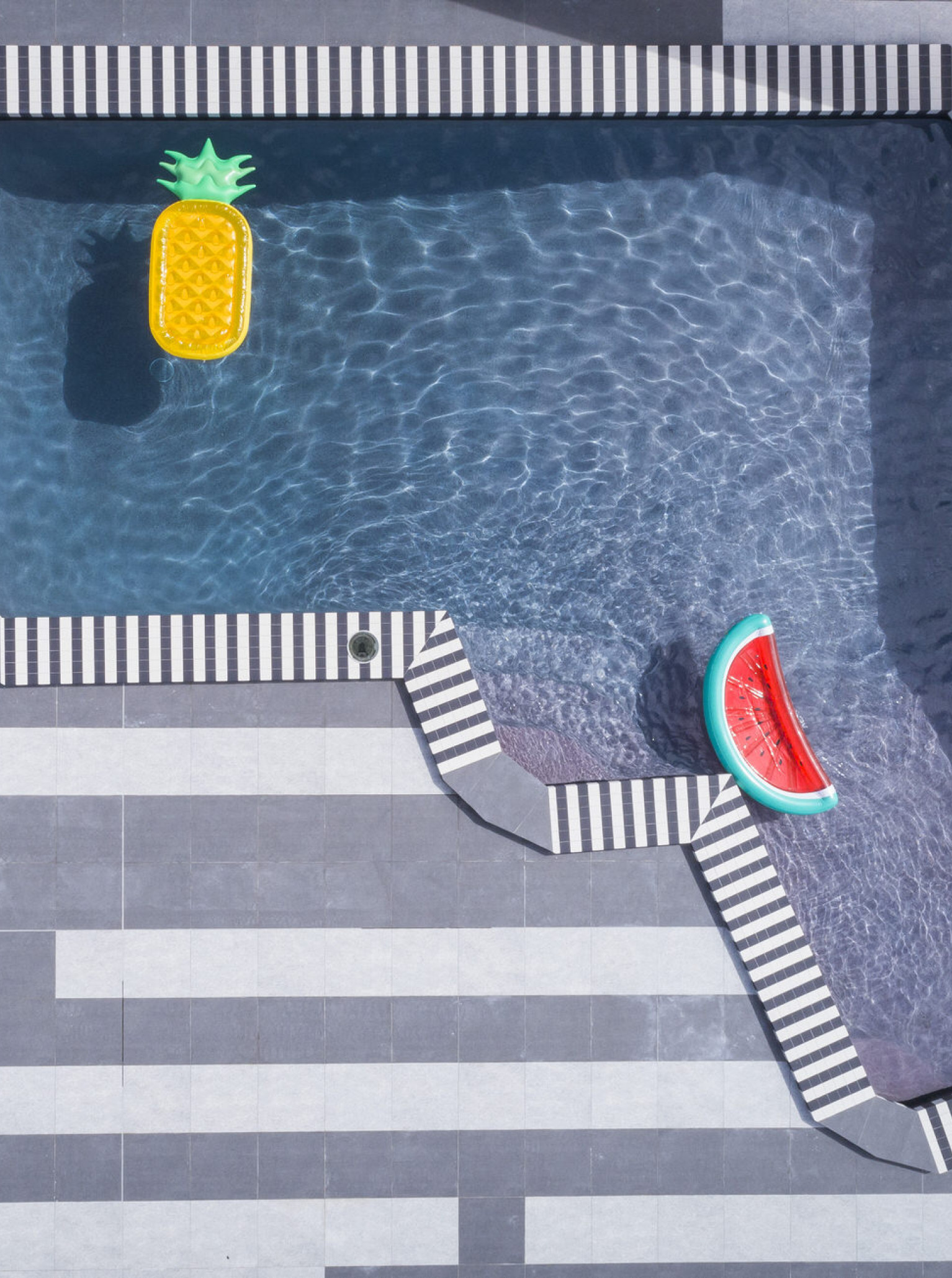 The outdoor swimming pool at Naumi Auckland Airport features a playful, contemporary design with bold striped edging.