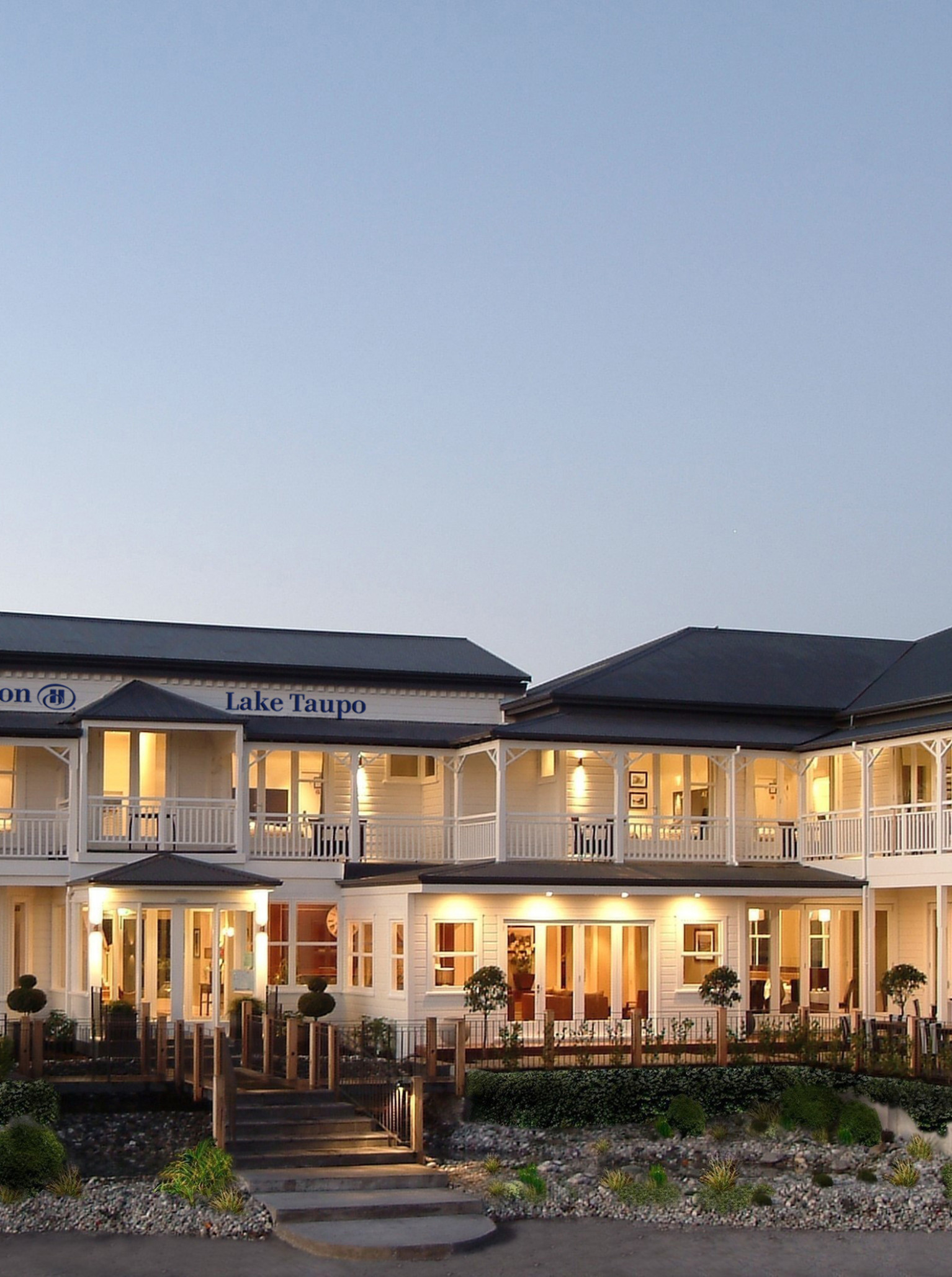 The Victorian-style heritage exterior of Hilton Lake Taupo features illuminated balconies and inviting outdoor dining.
