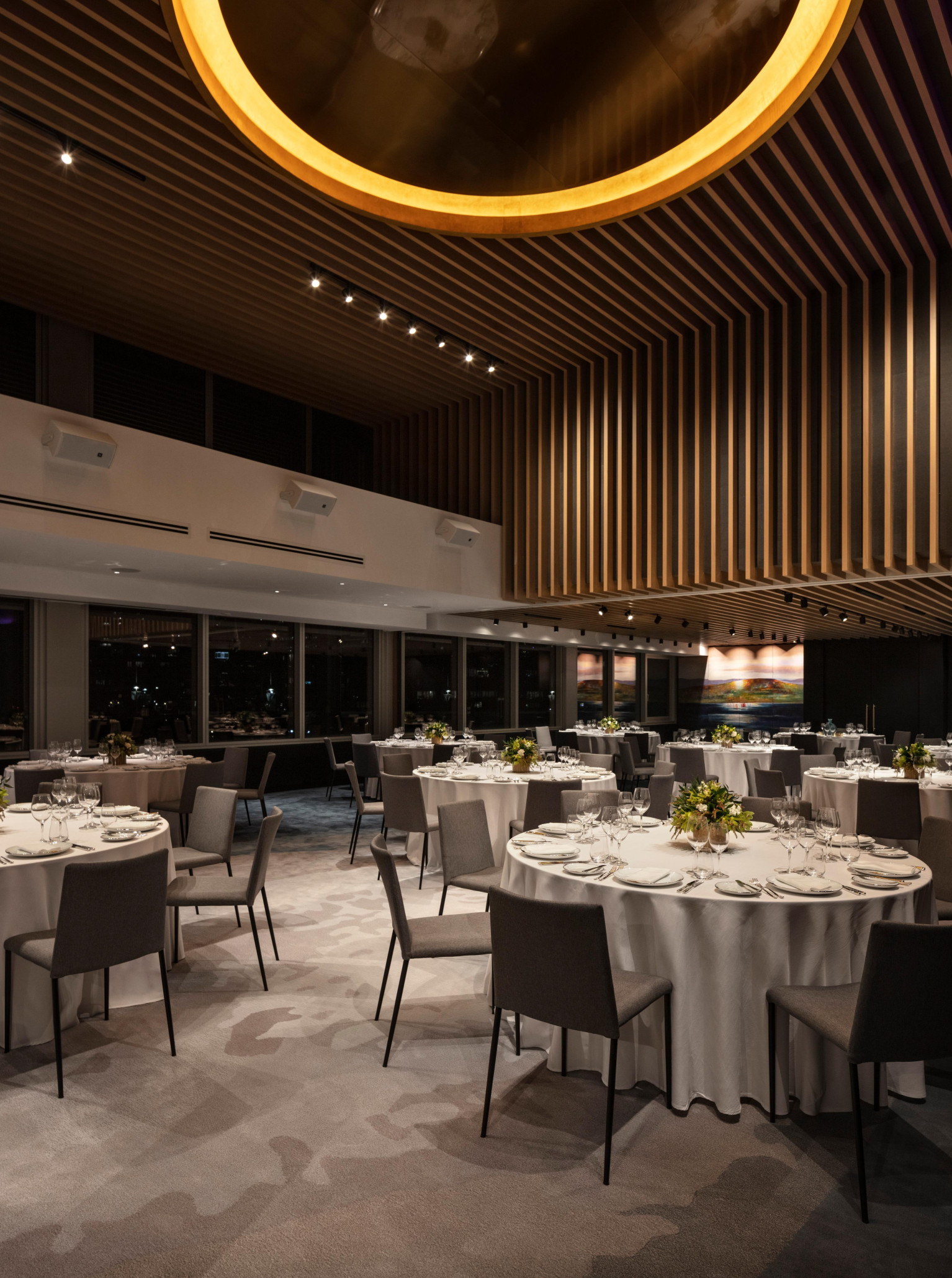 Elegant, modern event space at Park Hyatt Auckland, featuring a distinctive slatted wood ceiling and set for dining with city views.