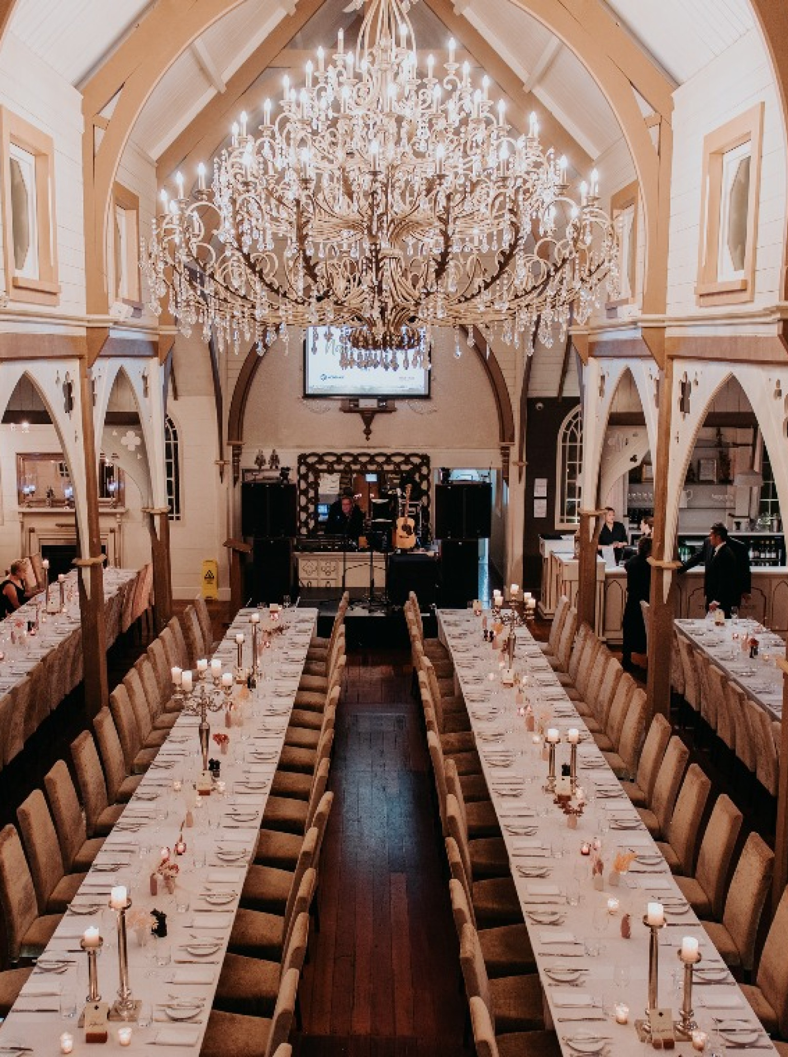 A grand dining hall set for an elegant event at the historic Old Church in Hawke's Bay, featuring a majestic chandelier.