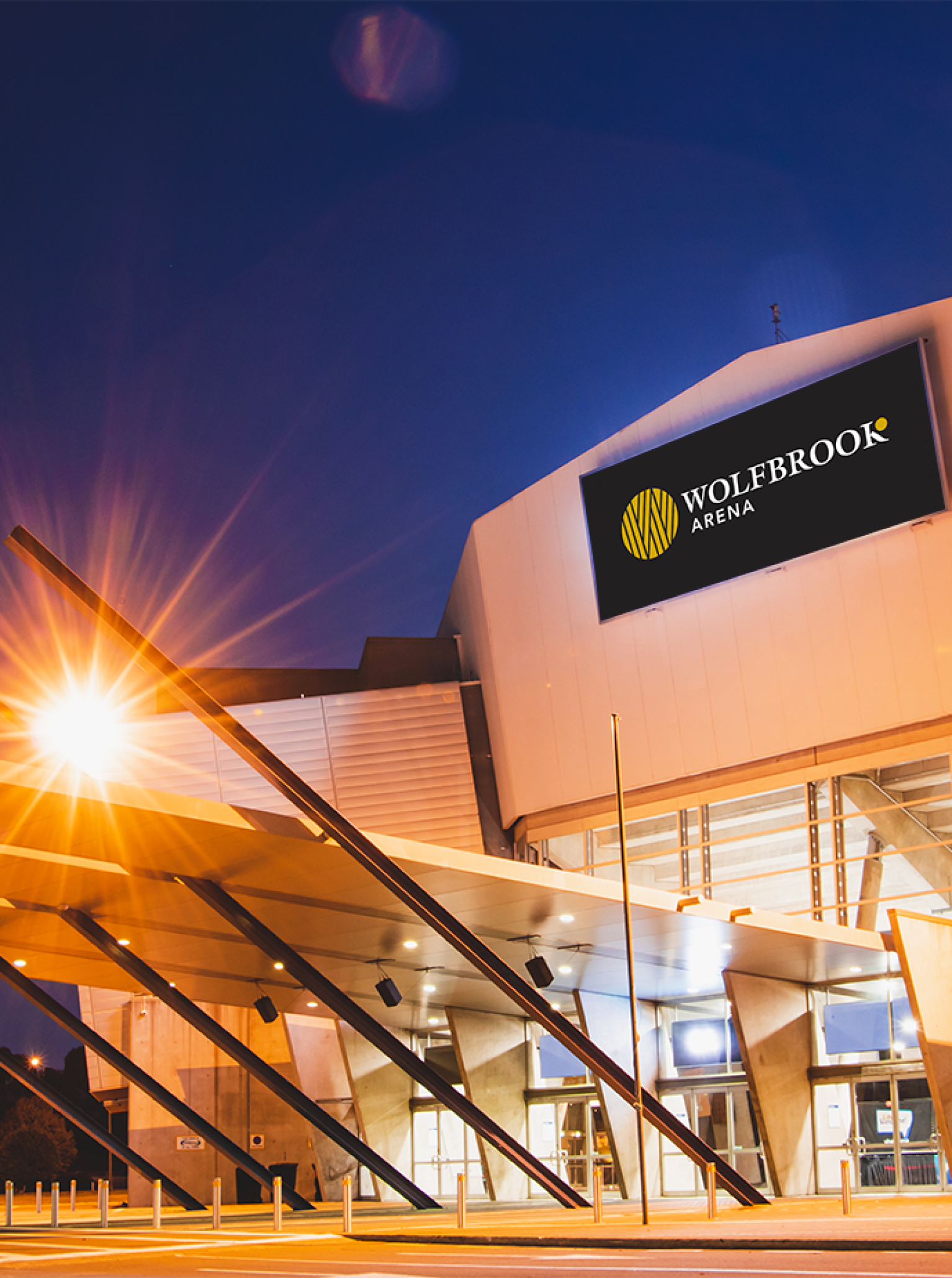 Night view of Wolfbrook Arena in Christchurch, showcasing its brightly lit, modern architectural exterior.