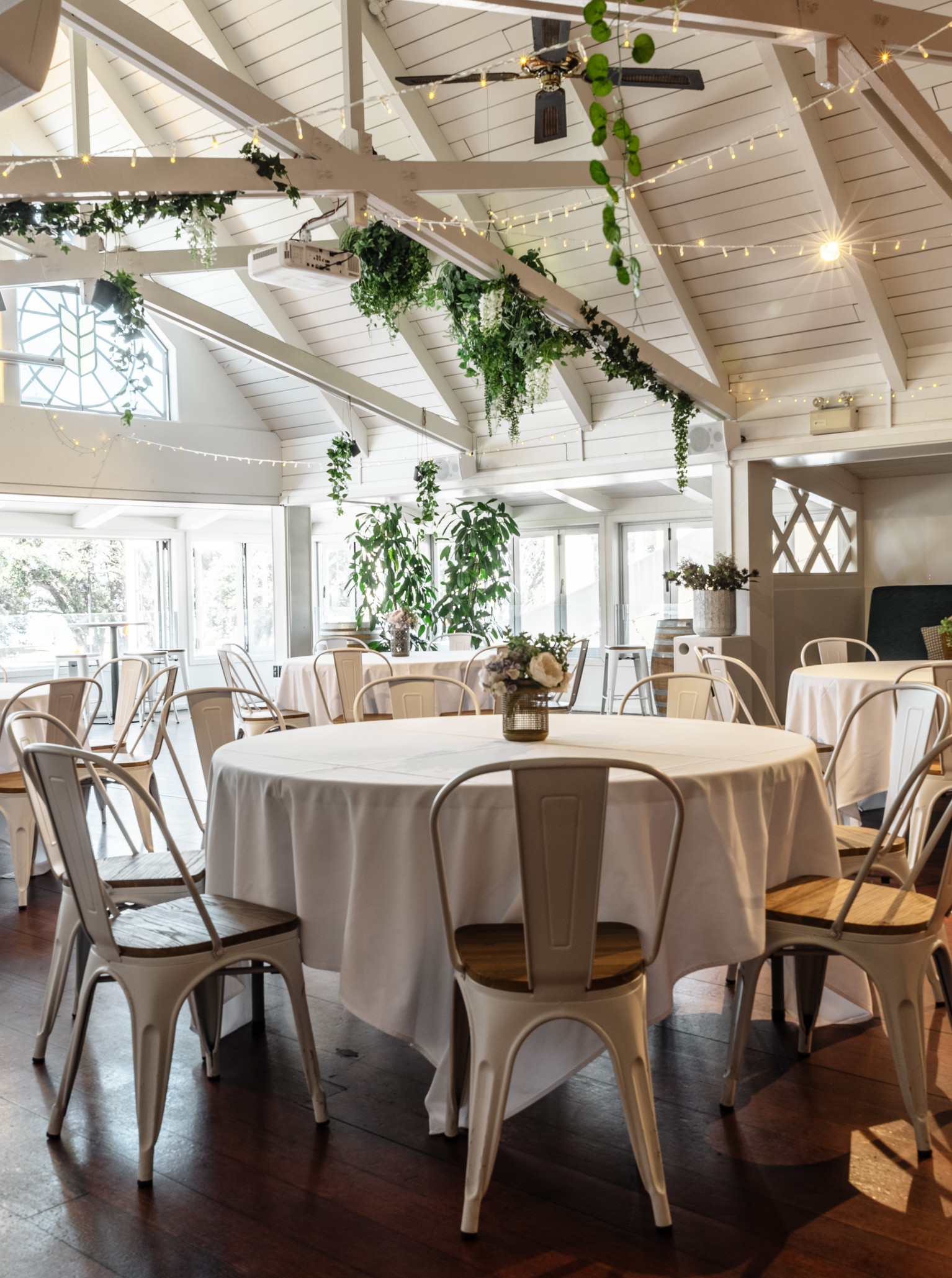 Mission Bay Taproom in Auckland offers a sophisticated event dining room with a high A-frame ceiling, decorated with fairy lights and greenery.