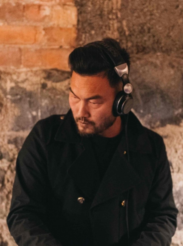 A DJ from Find a DJ Auckland working in an industrial-style setting featuring rustic brick and stone walls.