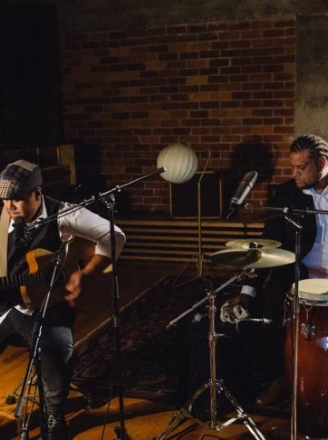 Taotua Duo performs soulful acoustic guitar and percussion in an intimate, brick-walled venue in Auckland.