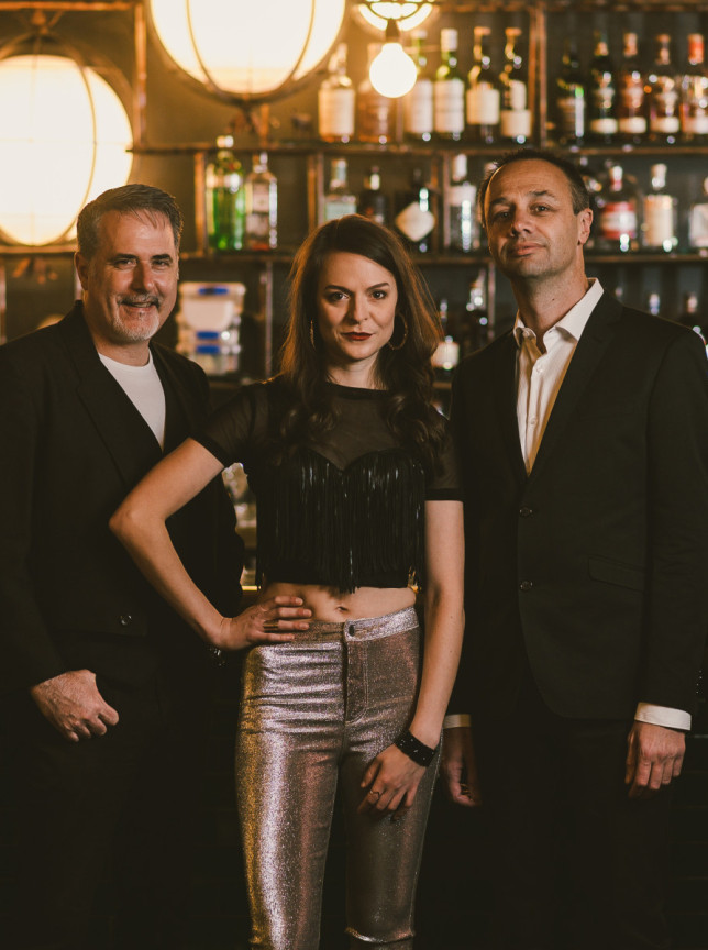 The Hustle, a Wellington covers band, poses in a stylish, dimly lit bar setting.
