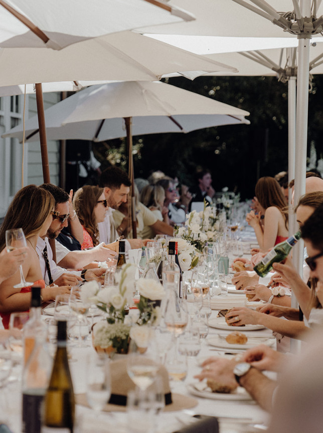 LittleWolf's elegant outdoor dining event in Auckland features guests enjoying a meal under white umbrellas.