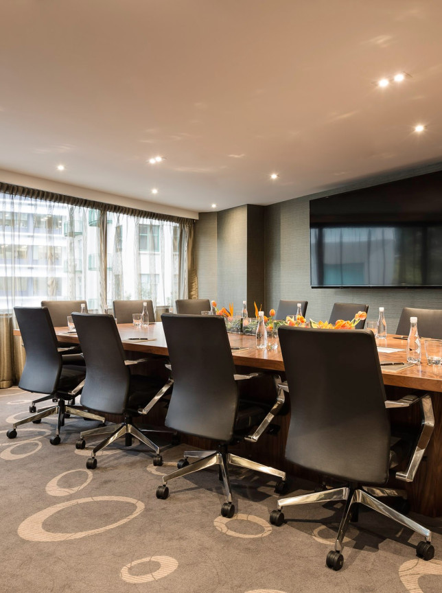 An elegant, French-inspired boardroom at Sofitel Wellington, featuring a large wooden table and modern screen for productive meetings.