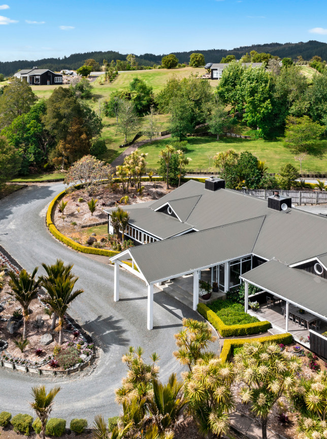 Aerial view of Woodhouse Mountain Lodge, Auckland, showcasing its contemporary lodge architecture amidst rolling green hills.