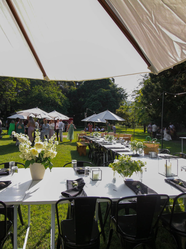 An outdoor dining event unfolds within the picturesque garden setting of Omatua, a rural riverside lodge in Hawke's Bay.