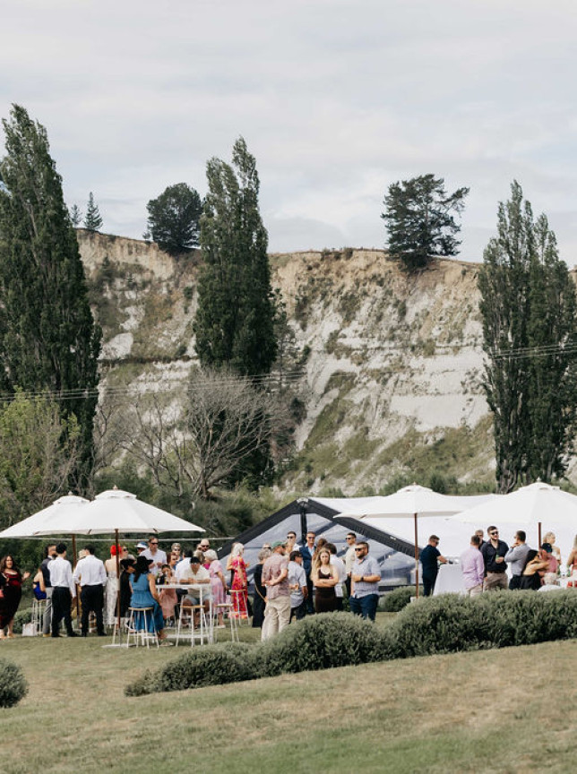 Guests enjoy an outdoor gathering at Omatua, a rural country venue in Hawke's Bay, featuring expansive lawns and natural surroundings.