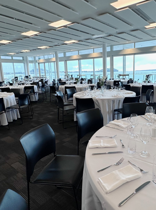 The modern event room at Akarana at Hyundai Marine Sports Centre, Auckland, is set for dining with panoramic Waitematā Harbour views.