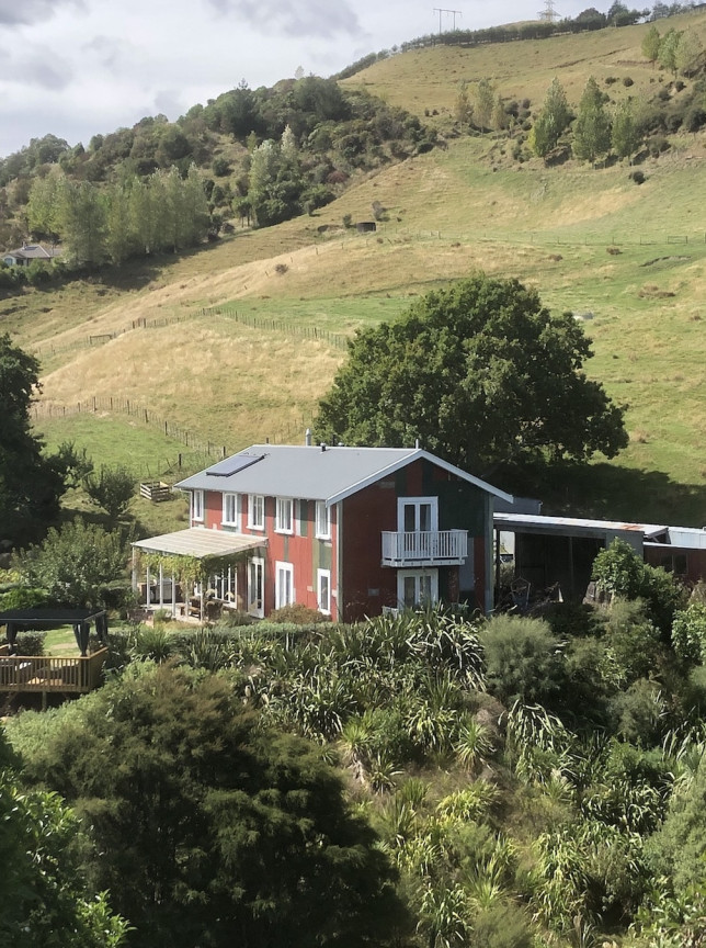 A rustic, barn-inspired Pear Orchard Lodge in Nelson-Tasman, featuring an outdoor event space among verdant hills.