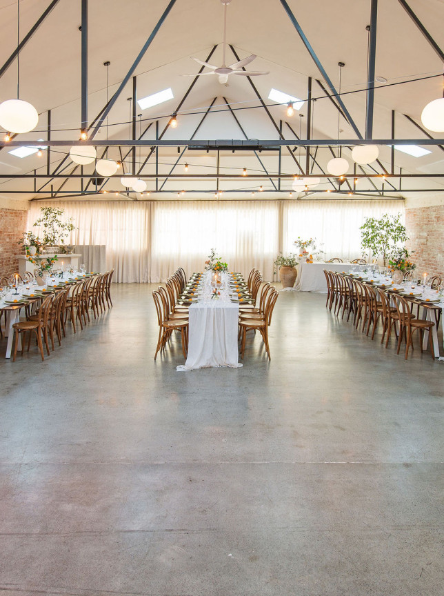 Dining tables arranged in the spacious, industrial-chic loft venue, Whisky & Wood in Wellington, with exposed brick and high ceilings.