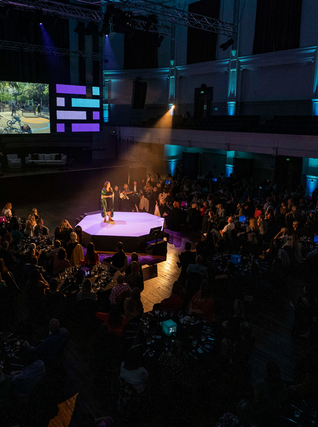 A speaker presents to a large audience in the grand baroque auditorium of The Dunedin Centre, Dunedin.