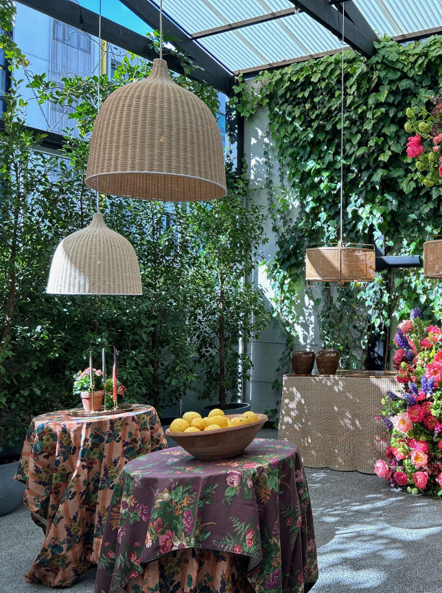 A chic, green-covered courtyard event space at Space On Crummer, Auckland, with lush floral arrangements and wicker lighting.