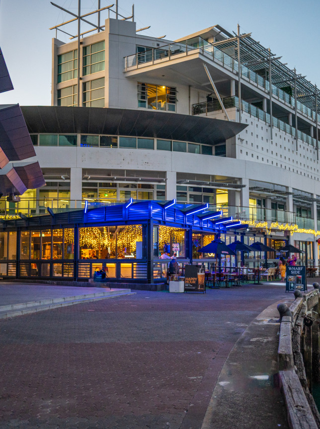 A modern, illuminated outdoor dining and bar area at Wharfside Function Centre, Auckland, overlooking the waterfront.