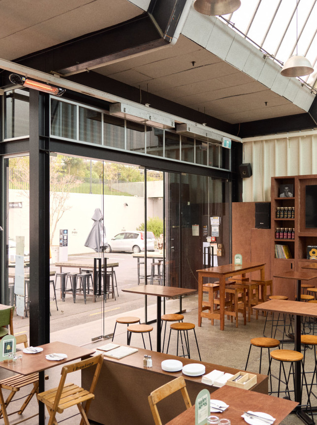 An industrial-chic dining area with mahogany tones and natural light fills Norma Taps in Auckland.