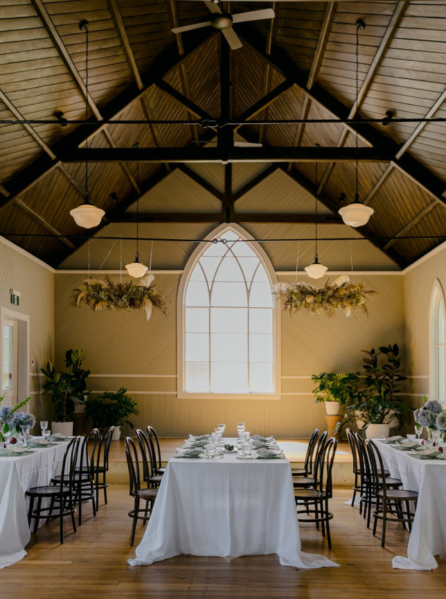 A formal dining setup in the historic Waikākā Church, Queenstown, showcasing its restored chapel architecture with arched windows.