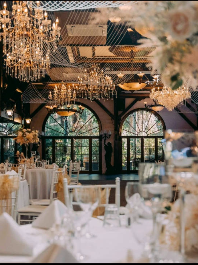 Settlers Country Manor, Auckland's heritage manor, hosts a vintage-elegant reception hall with grand chandeliers and arched windows.