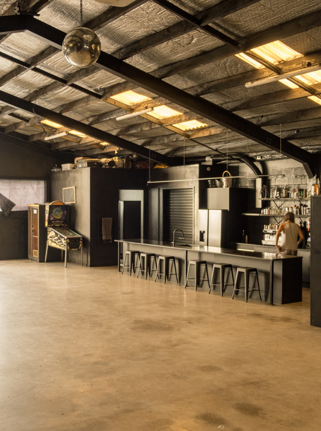 An industrial-chic event space at Hastie in Auckland, featuring a large open floor plan and a well-equipped bar.