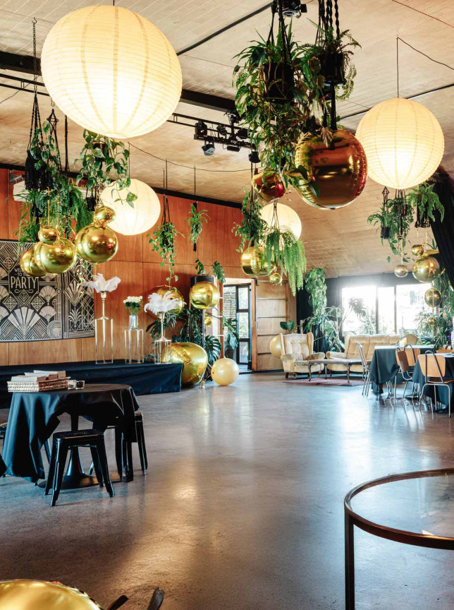 Evil Genius's Lair event space in Christchurch features a rustic and elegant setting adorned with lush greenery and warm, ambient lighting.
