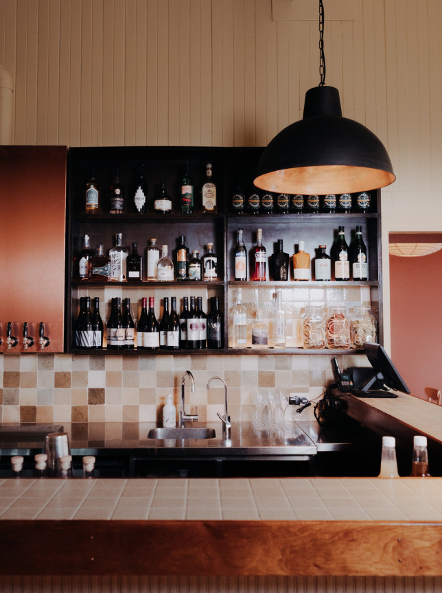 The lively bar area at Cuba Street Tavern in Wellington features textured timber, colourful tiles, and an industrial-chic pendant light.