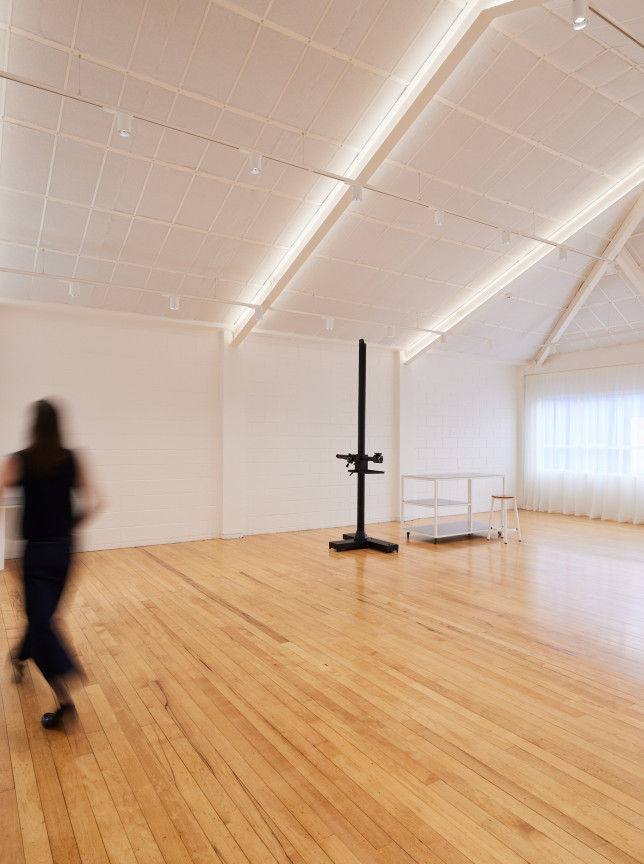 A bright, open modern studio at Common Space Studios, Auckland, featuring high vaulted ceilings, light wooden floors, and a makeup station.