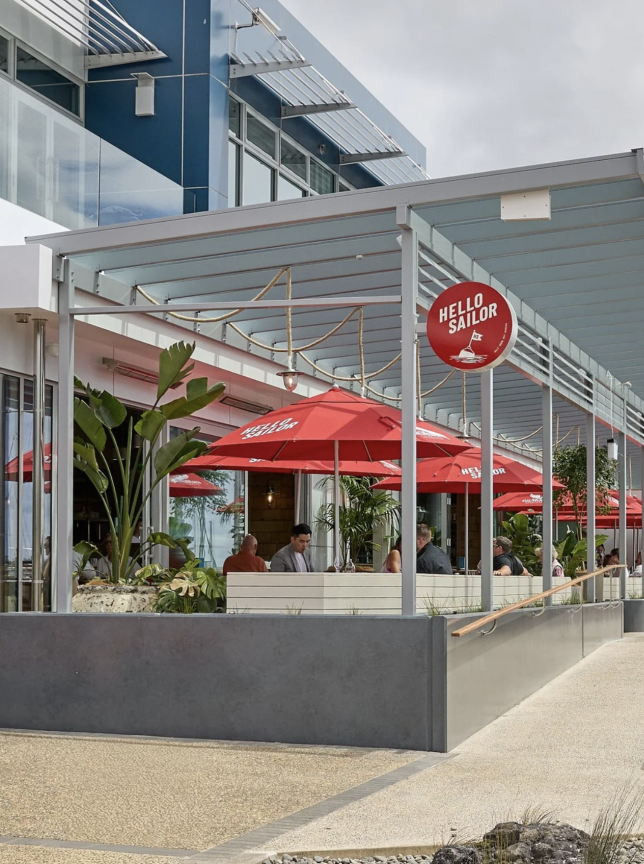 Outdoor dining patio with red umbrellas at Hello Sailor, an upscale seaside restaurant in Auckland's Half Moon Bay Marina.