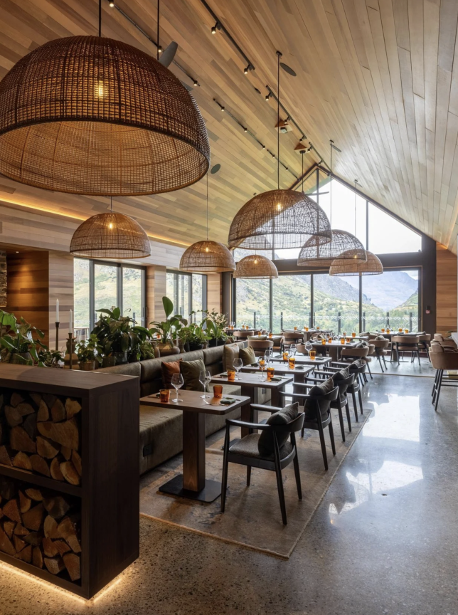 A modern alpine dining room at Coronet Ridge Resort, Queenstown, featuring natural wood, woven fixtures, and expansive mountain views.
