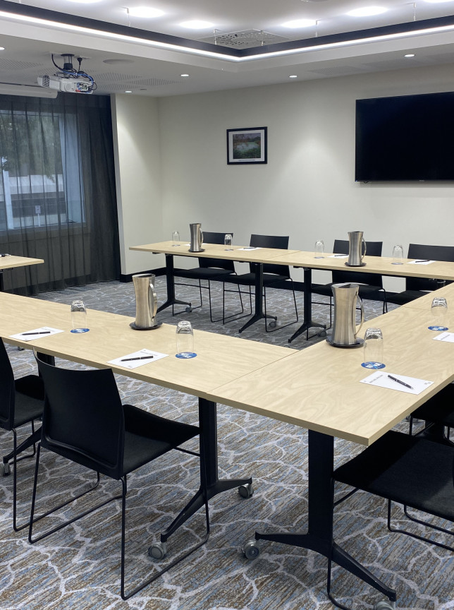 A modern U-shaped meeting room at Pullman Rotorua, featuring a sophisticated design with integrated AV technology for events.