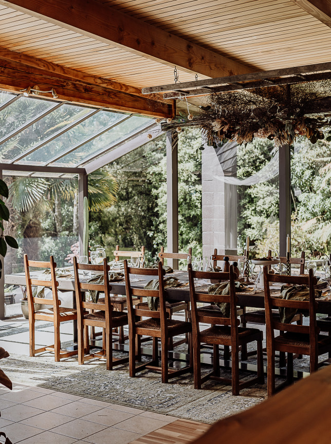 An intimate dining room is set within the light-filled glass atrium with timber beams at Enchanted on New Zealand's West Coast.
