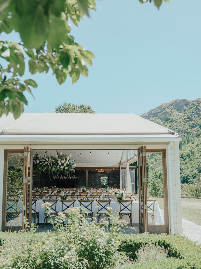 Elegant outdoor dining at Winehouse Queenstown's historic homestead pavilion, adorned with flowers and string lights.